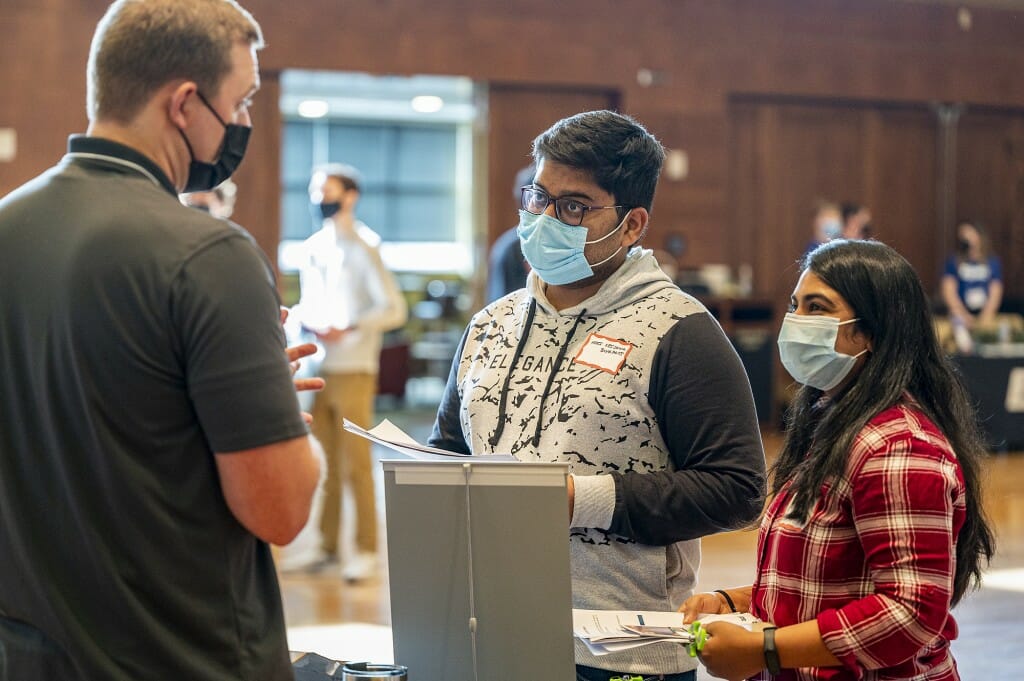 Students Hari Krishna Boyapati (center) and Harshita Edugudi (right) speak with a representative from Gainwell Technologies.