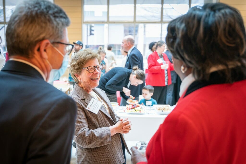 Blank laughing while visiting with 2 people at a reception in the lobby of the Discovery Building