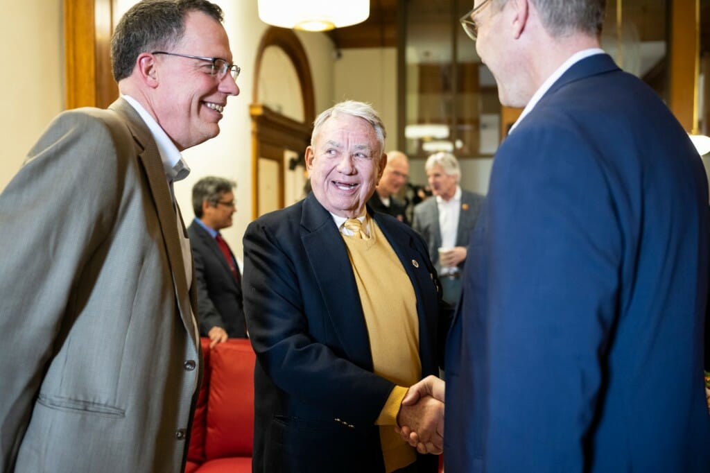 Thompson, center, talks with UW–Madison Provost Karl Scholz, left, and UW–Madison Director of Athletics Chris McIntosh, right.