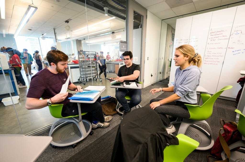 Three people sitting in chairs in a classroom