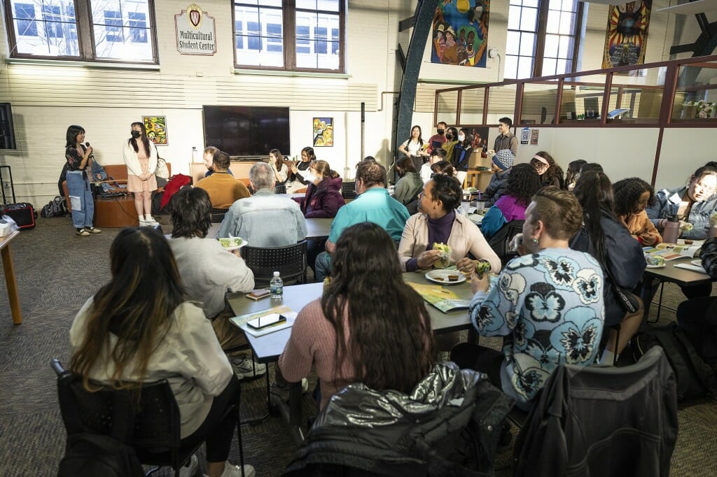 Standing at the front of the room, planning committee members Manola Inthavong, at far left, and Juliet Chang, second from left, make introductory comments for the art show.