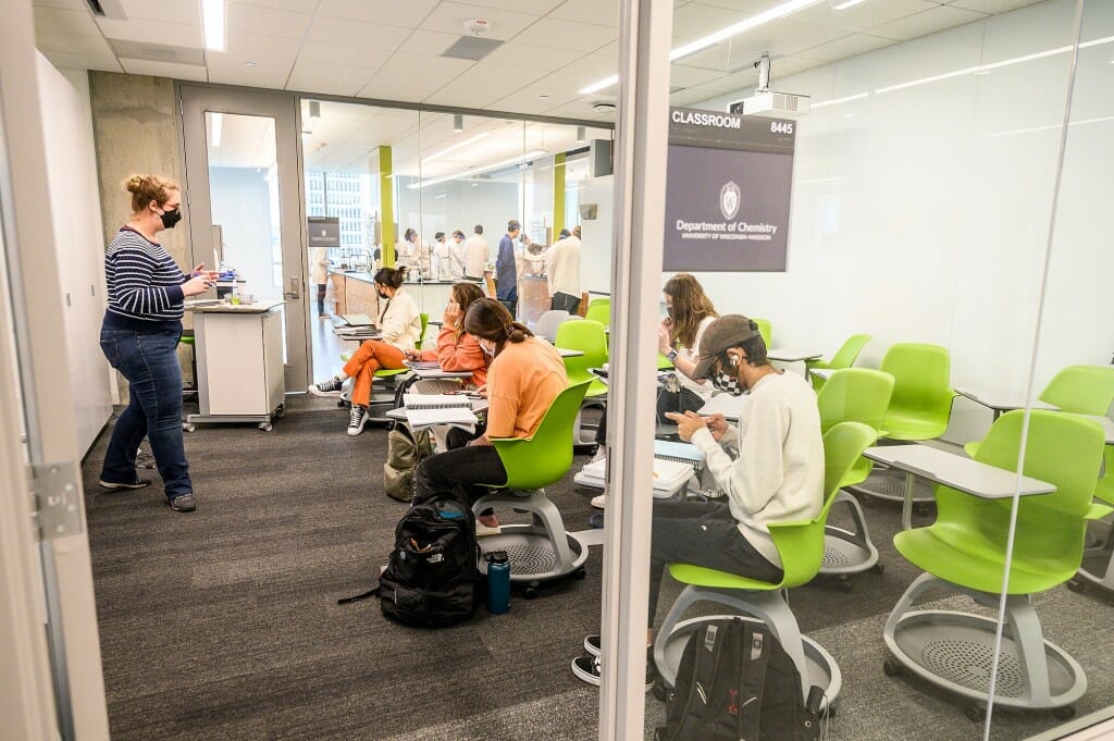 Students sitting in a classroom, with students in a lab visible behind