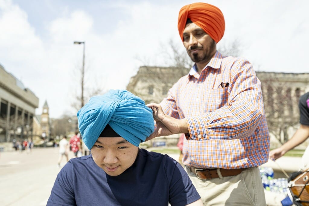 UW alum Gursharan Singh (right) ties a turban on UW student Jaewon Choi.