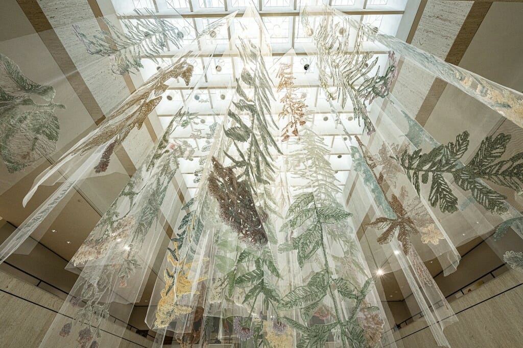 View from floor level looking up at skylights from which large embroidered plants are suspended