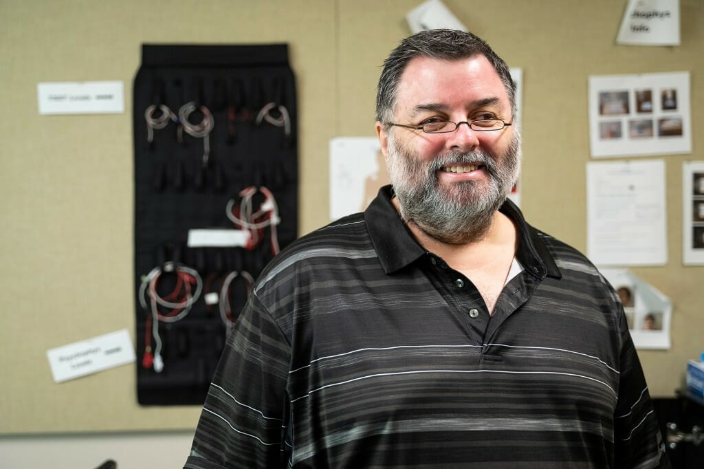 John Koger posing in front of some IT equipment on a wall