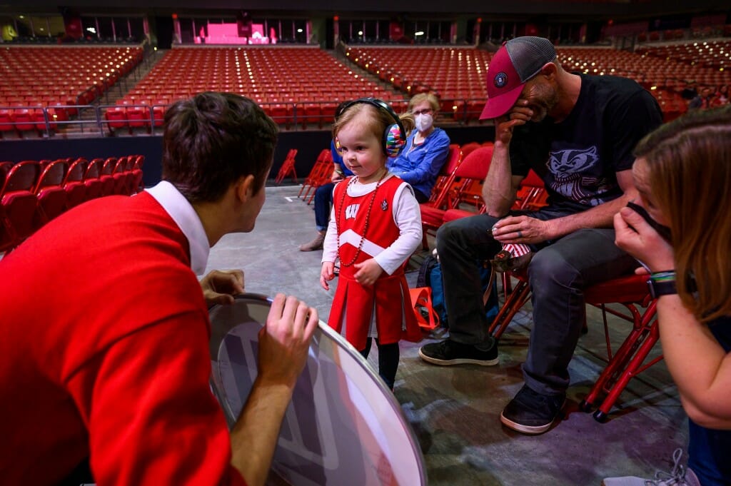 At left, Josh Richlen, drum major and tuba player, offers Ila a drum cover signed by all the members of the tuba section while Ila’s parents Jadon Scullion and Dana Hellgren look on.