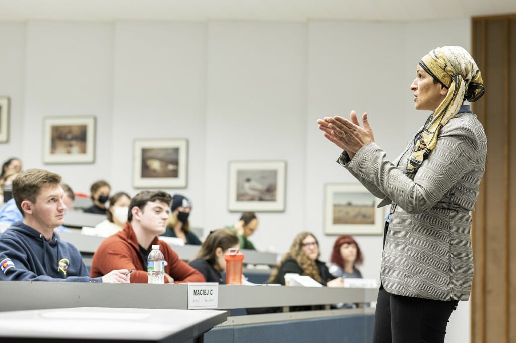 Asifa Quraishi-Landes standing in front of a lecture hall with students sitting at desks