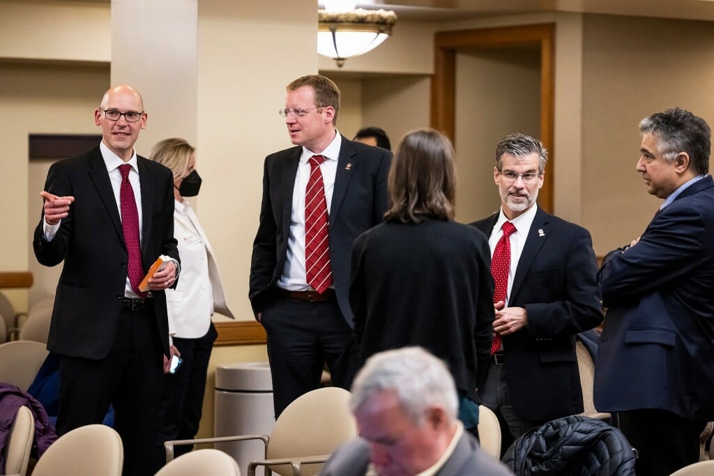 Several people wearing dark suits standing and talking with each other