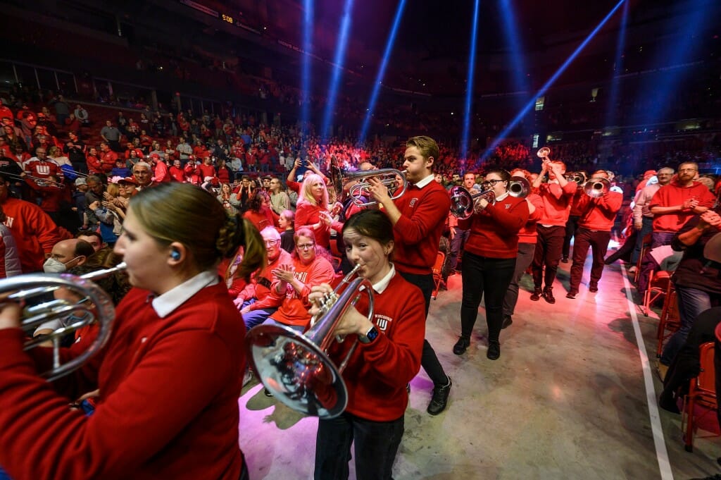 Band members march through the aisles while audience members clap along.