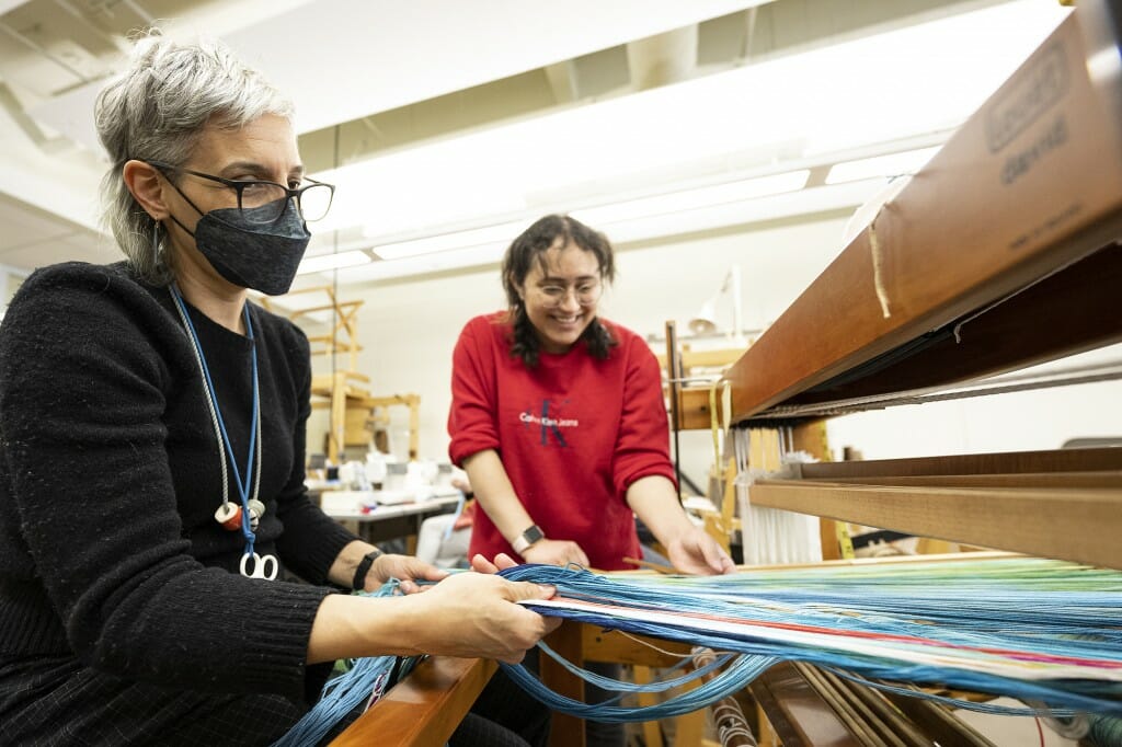 Assistant Professor Marianne Fairbanks (left) works with student Bryanna Milligan (right) during the Textile Design: Weaving I class, as part of the Arts Crawl.