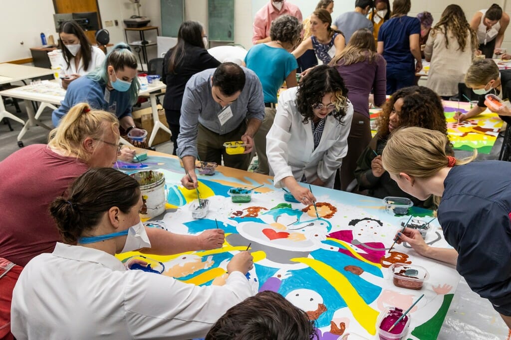 People paint a mural on a table.