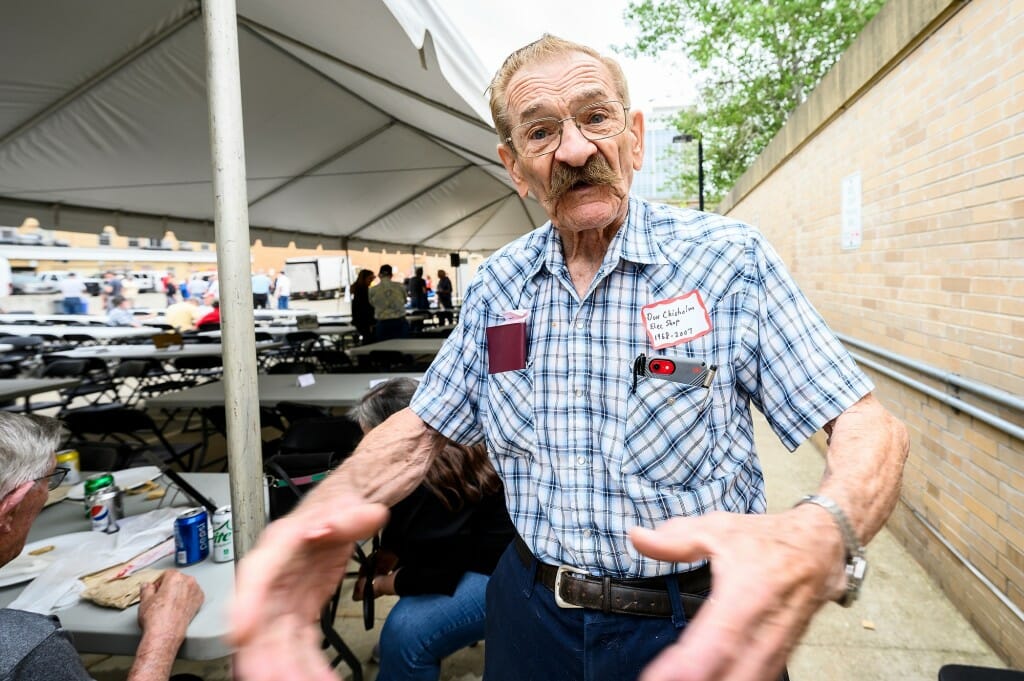 A man in a plaid shirt gesticulates.