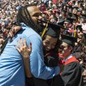 A graduate and another person embracing and smiling in the crowd