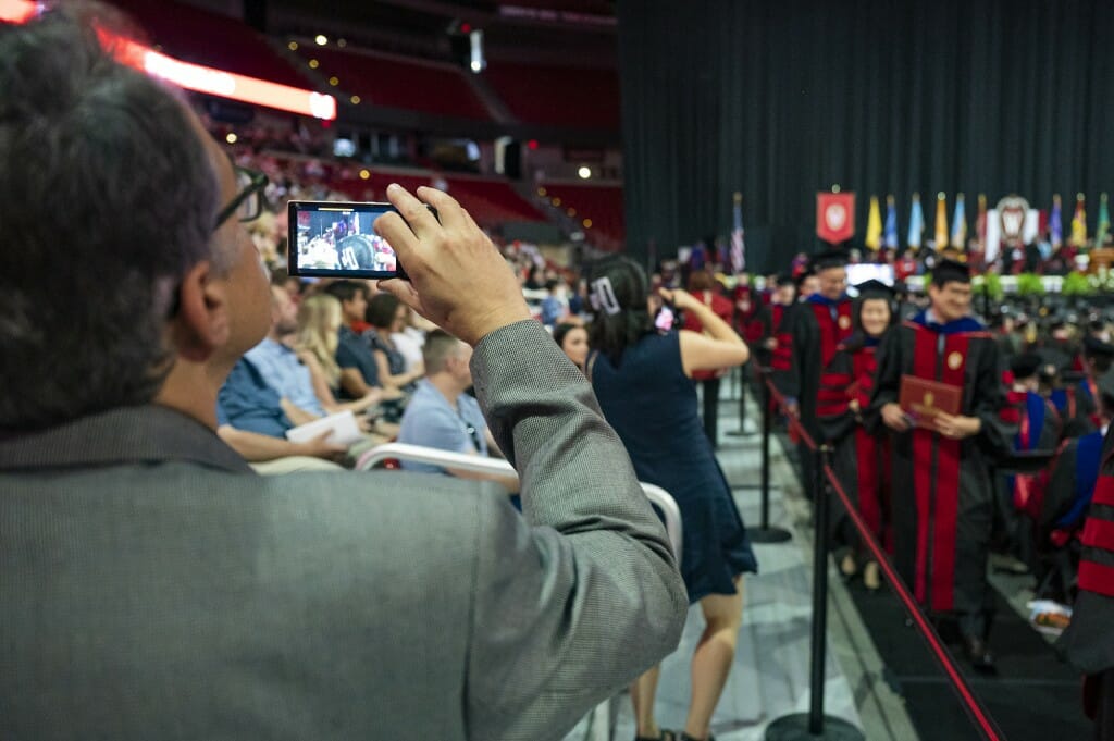 Person taking a photo of a student in cap and gown