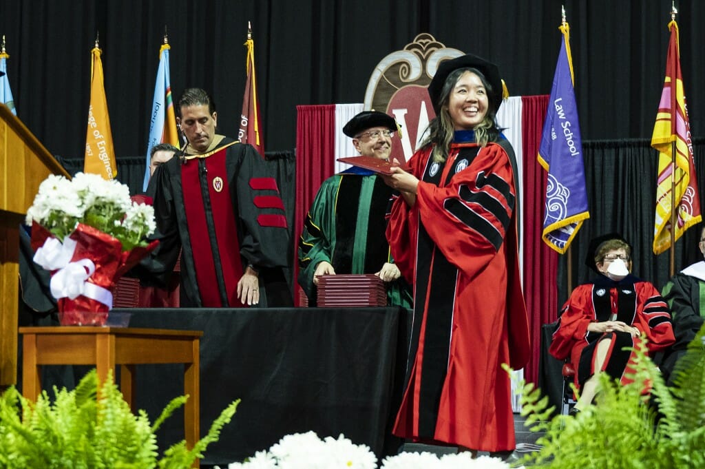 Person in cap and gown holding up diploma cover