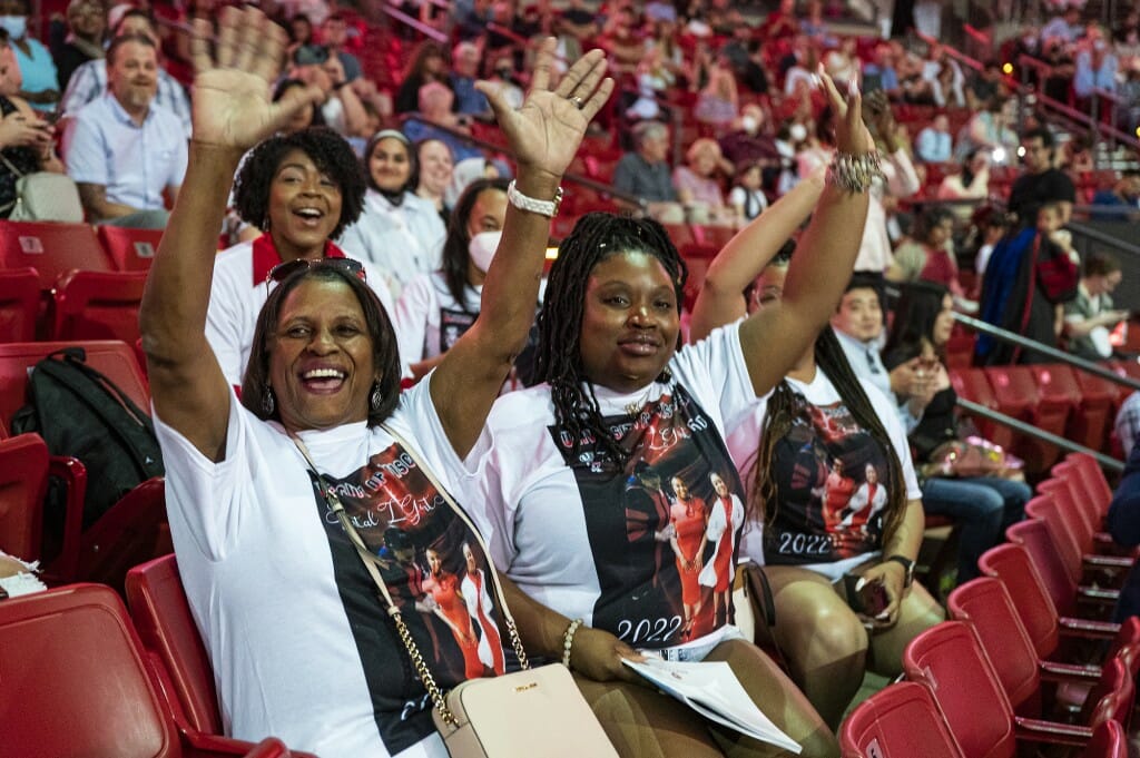 People in audience smiling and raising arms