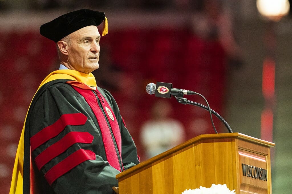 Nosbusch in academic cap and gown speaking at podium