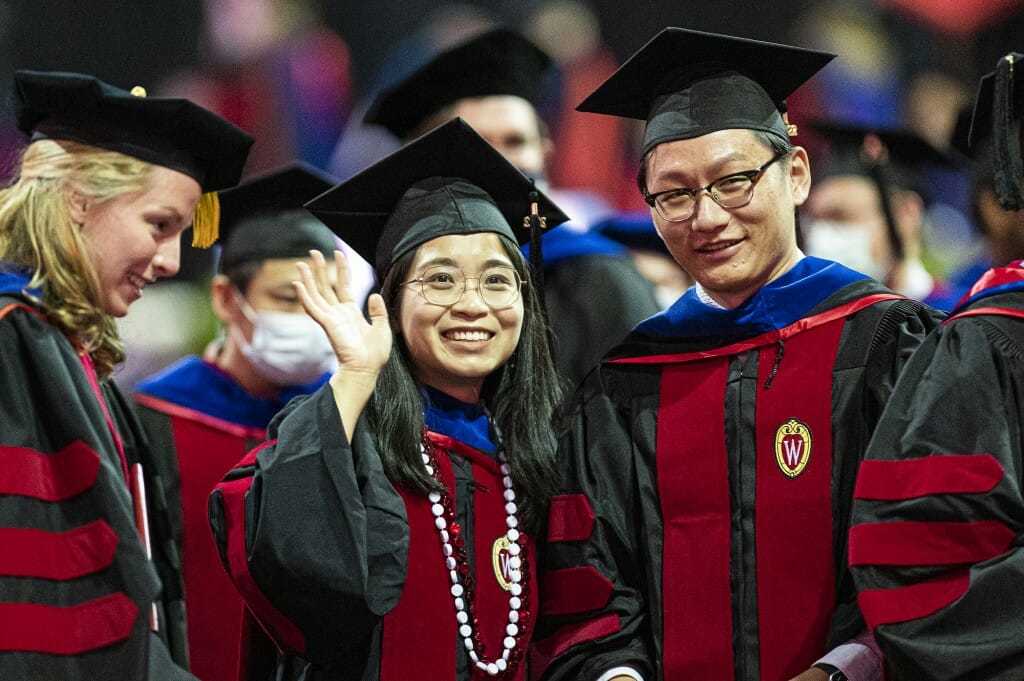 People in caps and gowns waving