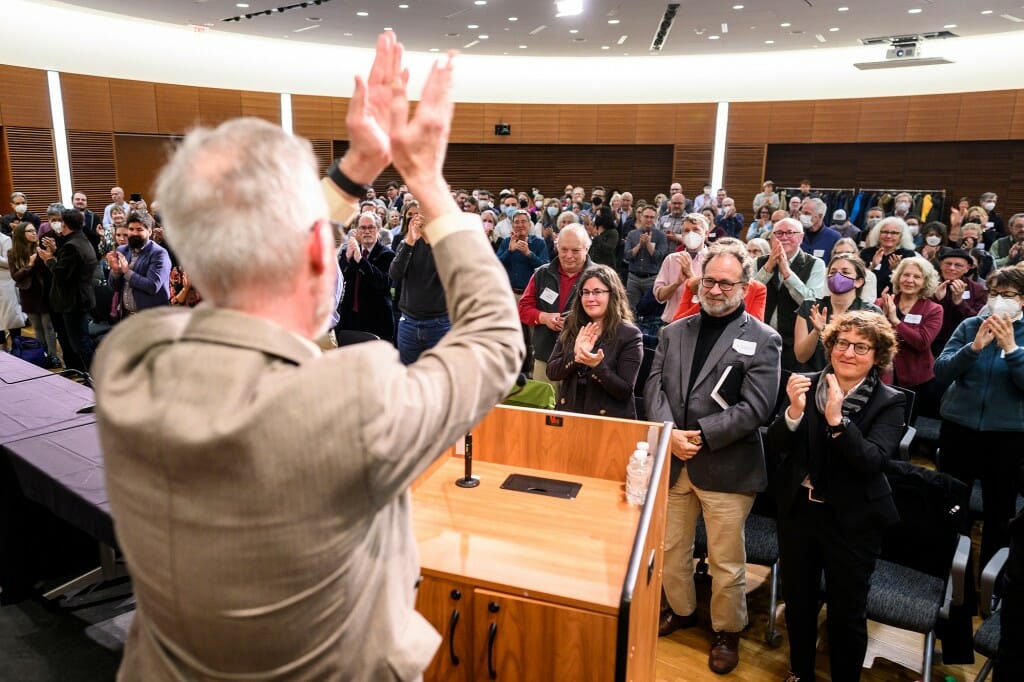 Cronon standing at podium, facing crowd, and clapping his hands