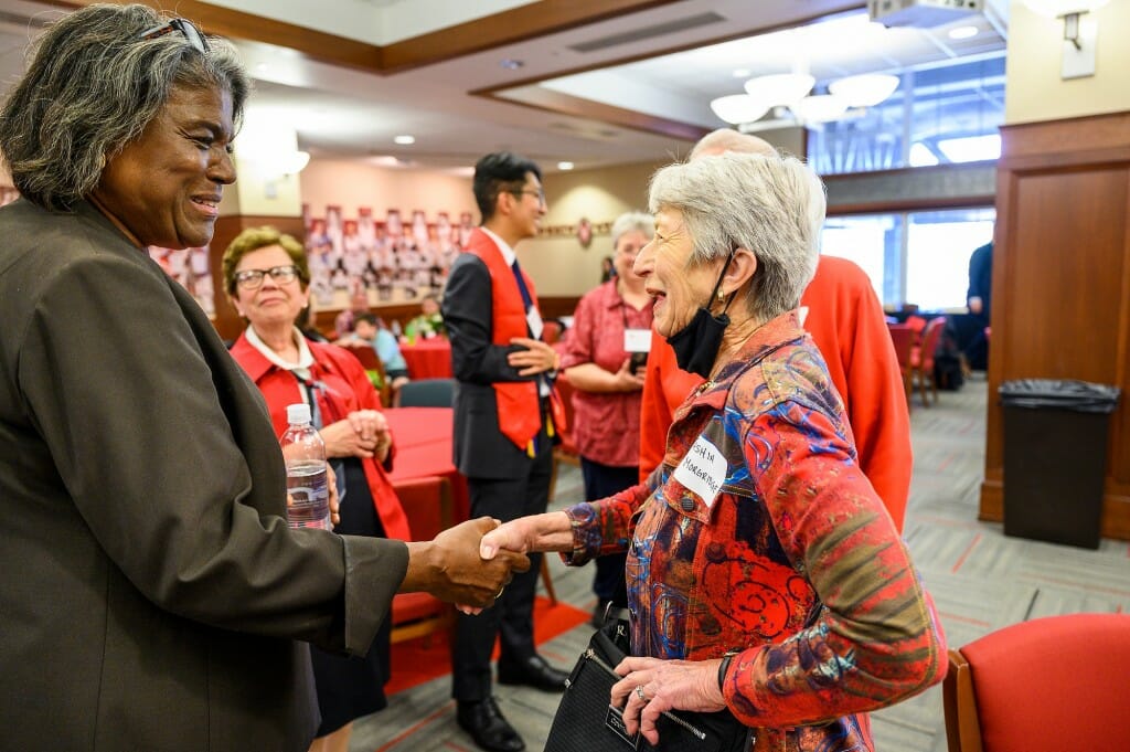 A woman and another woman shake hands.