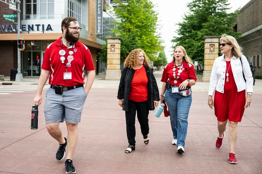 Mnookin, Reesor and tour guides walking across street between W-crest pillars