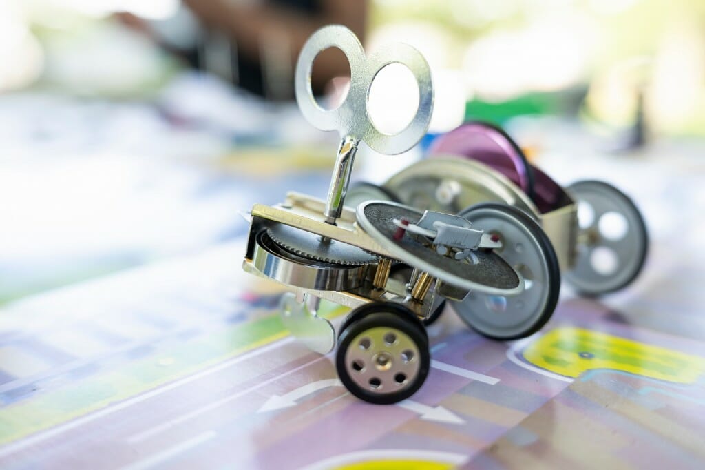 A metal windup toy with wheels, gears and a key