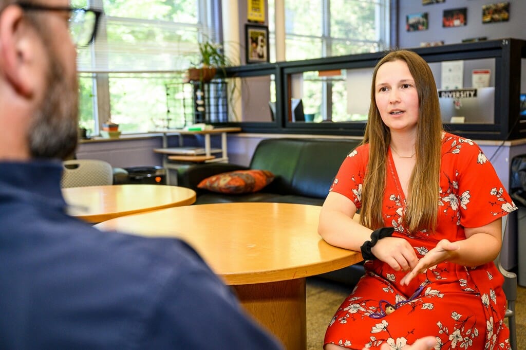 Strnad sitting at a table speaking with an unidentified person