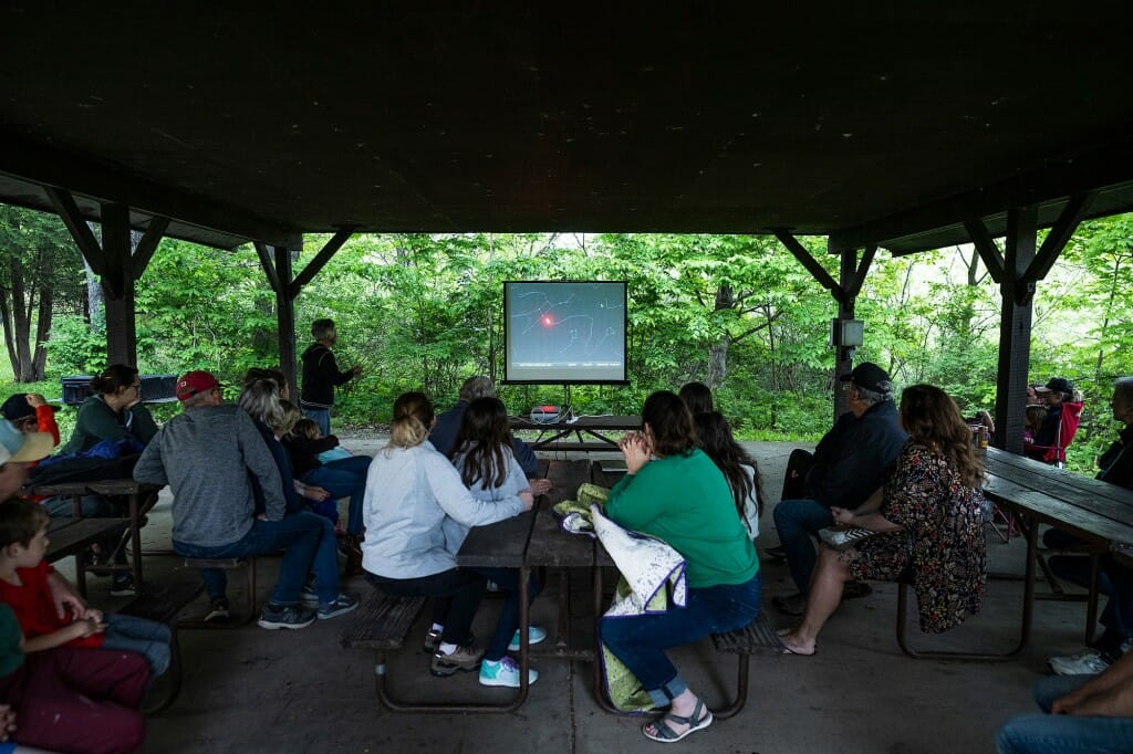 View from back of shelter of people watching a projection screen