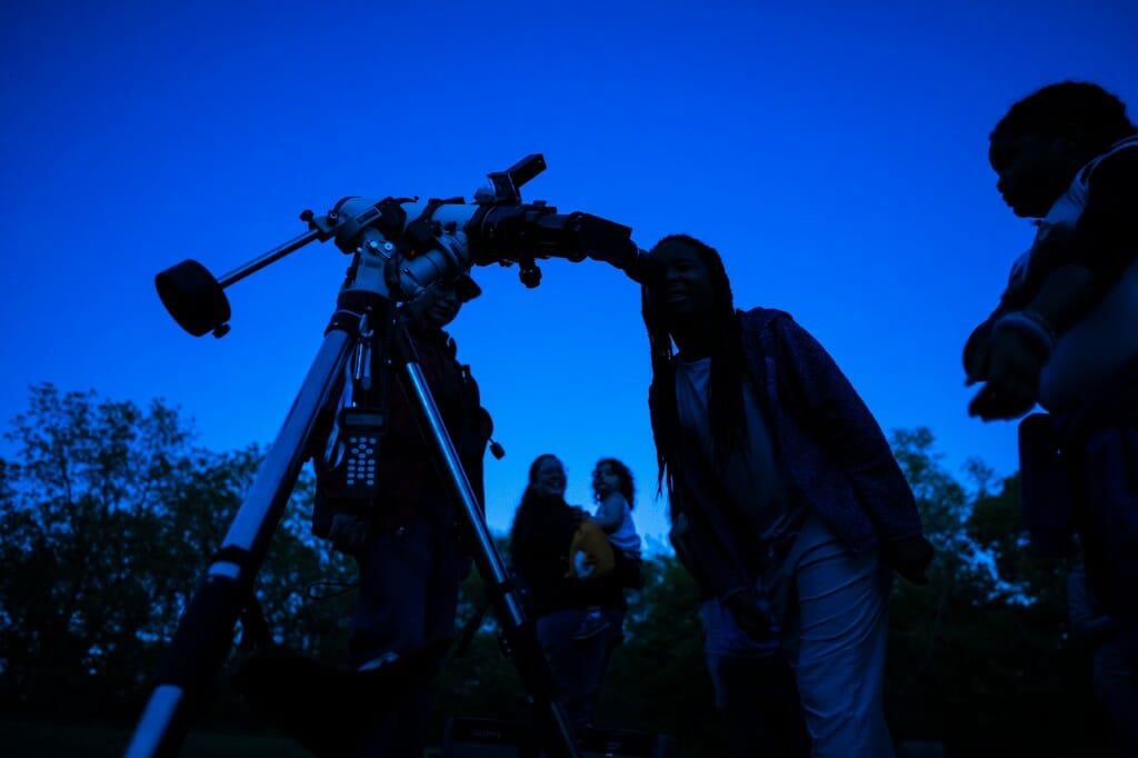 Silhouetted figure looking into telescope