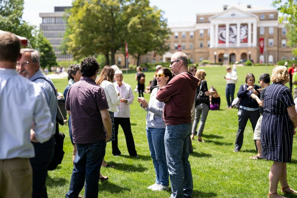 Several people standing and talking to each other in a crowd on the Bascom Hill lawn