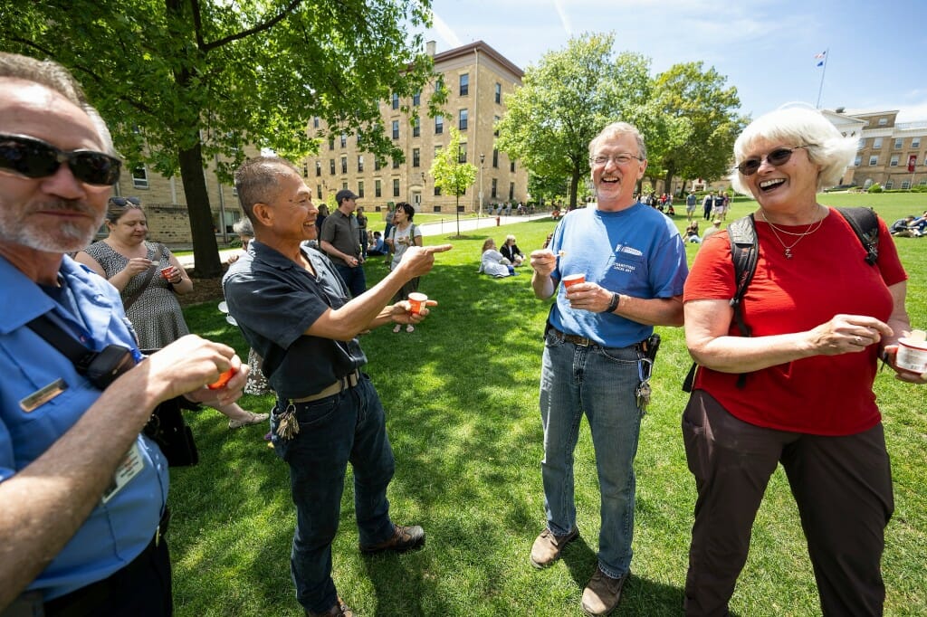 Several people standing in a group talking to each other on the Bascom Hill lawn