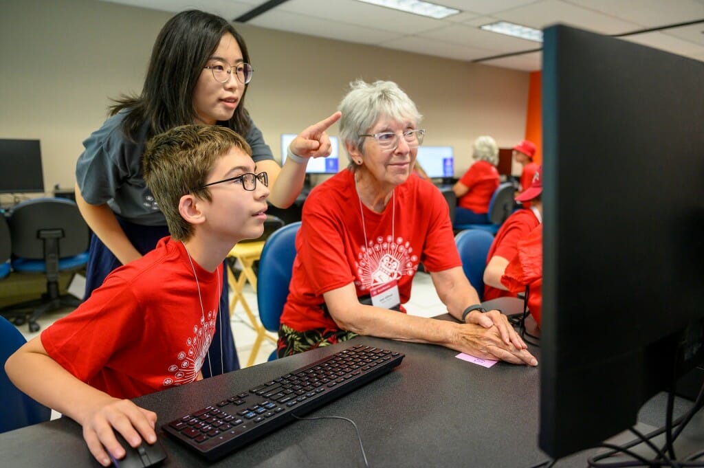 Two kids and an older woman look at a project.