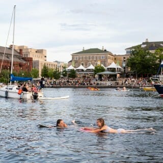 Two girls swim in a blue lake.