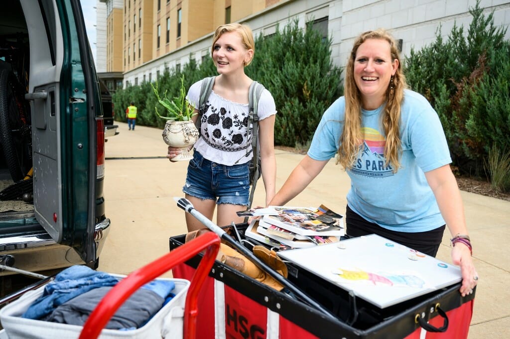 First-year student Cheyenne Schepp from Wausau holds a potted plant while her mom maneuvers the moving cart during the Dejope Residence Hall move-in.