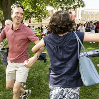 Two people link arms and dance.