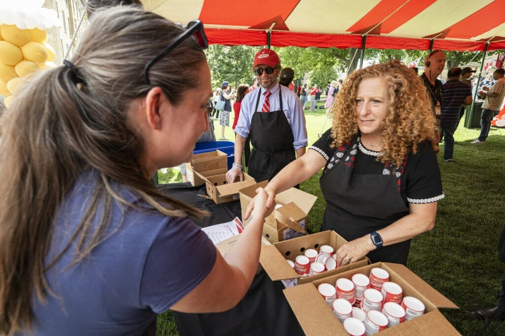 Chancellor Mnookin hands an ice cream container to a smiling woman.