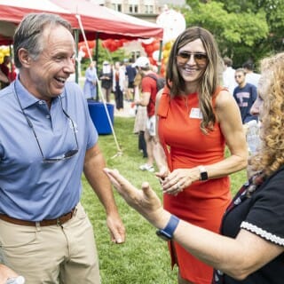 Two woman and a man stand and talk on the lawn of Bascom Hill, laughing in enjoyment.