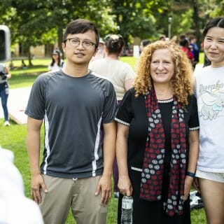 Three people pose for a photo together, standing on Bascom Hill.