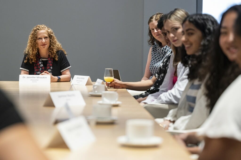 Chancellor Mnookin sits and listens at a table, as students are shown listening too.