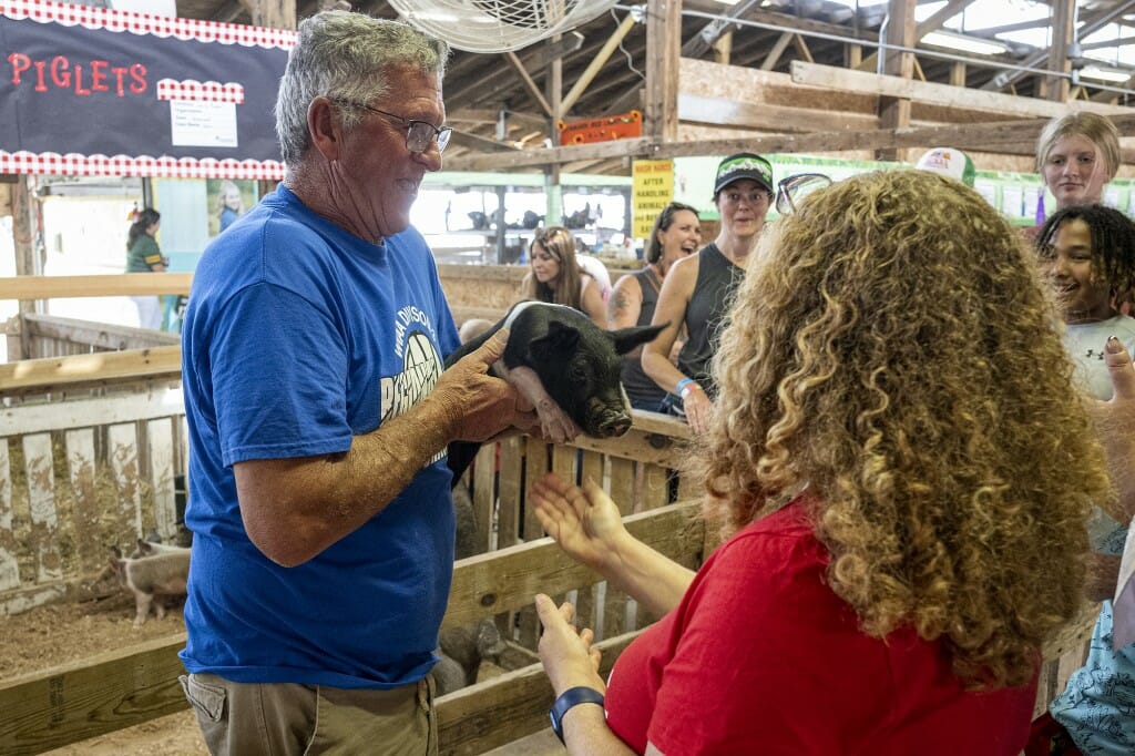 Chancellor Mnookin is handed a piglet while visiting with members of the local 4-H Club.