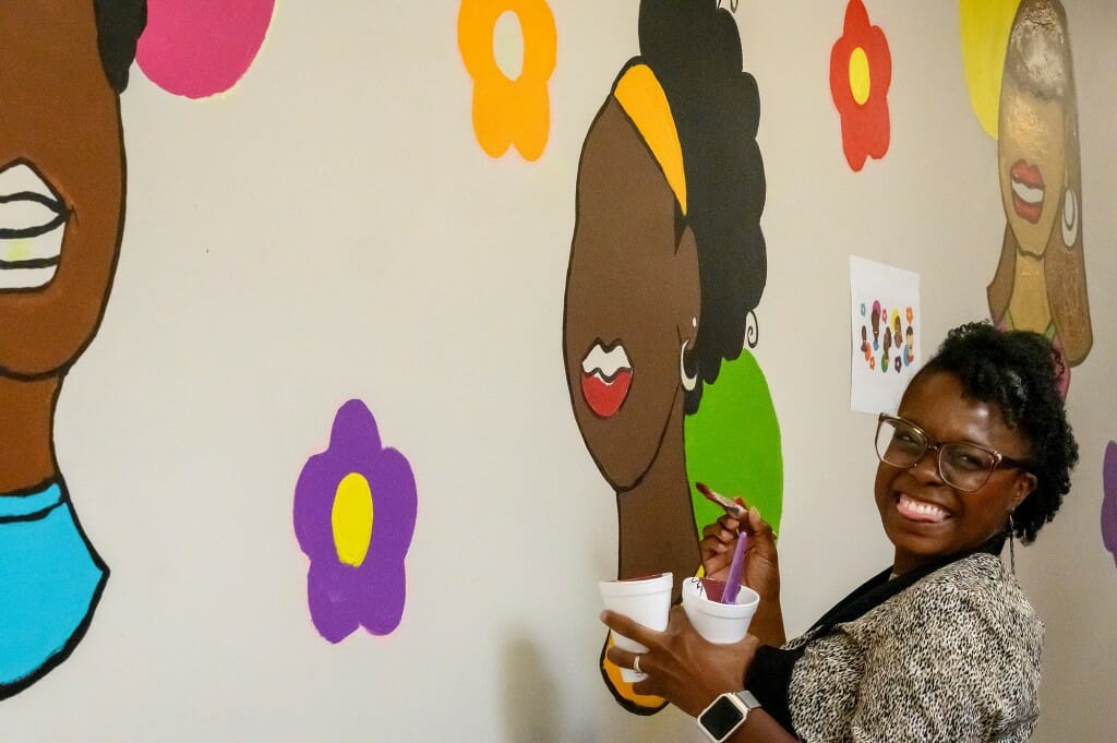 A woman paints on the mural.