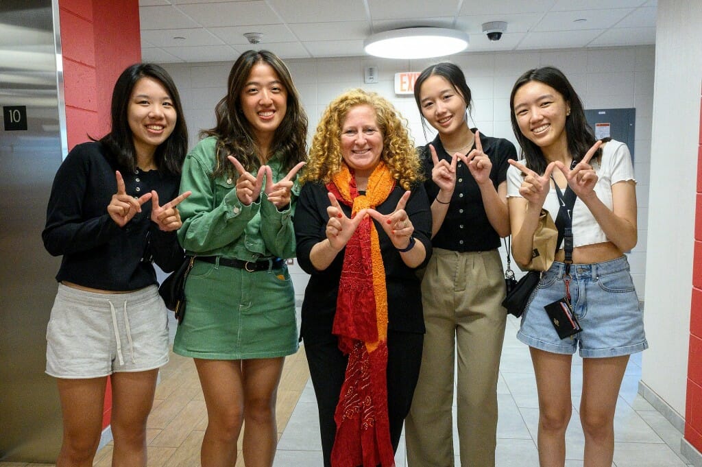 Five people hold up their hands in the W signal, while smiling at the camera.