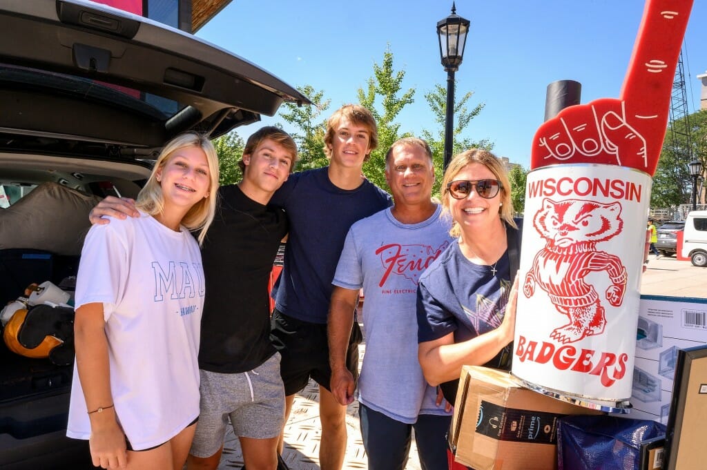 A group of people pose for a camera and smile, next to a van.