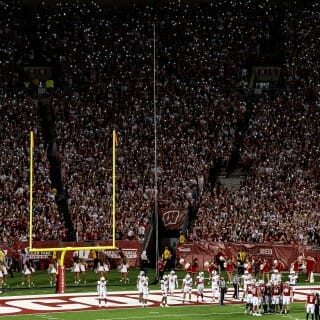 Individual lights sparkle in the dark football stands.