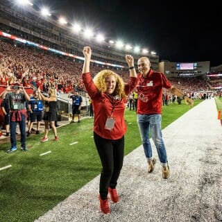 Two people dance on the edge of a football field.