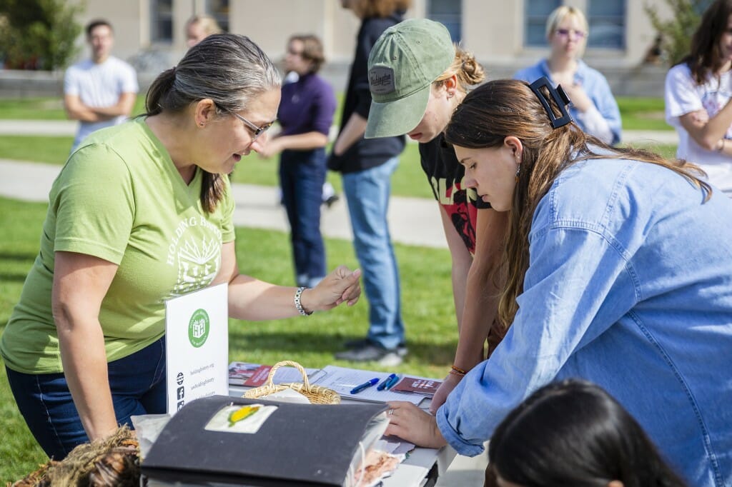 Sarah Marty speaks with a student while looking at handmade paper samples.