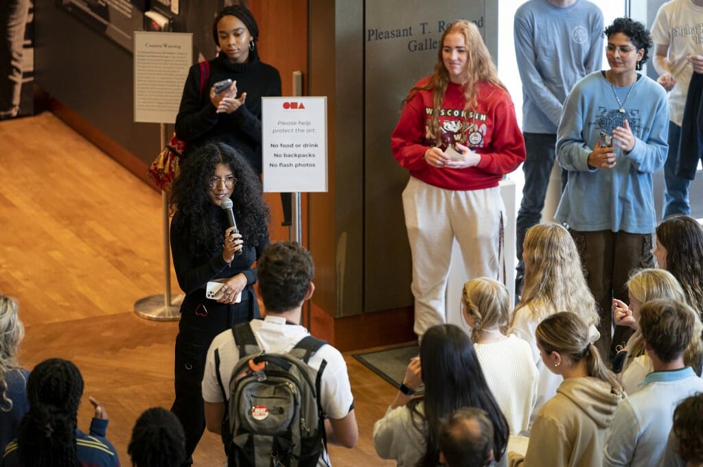 A woman speaks into a microphone as others listen.