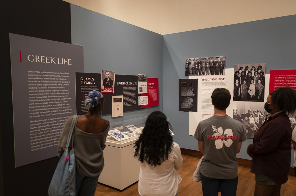 Four people stand at an exhibit titled 