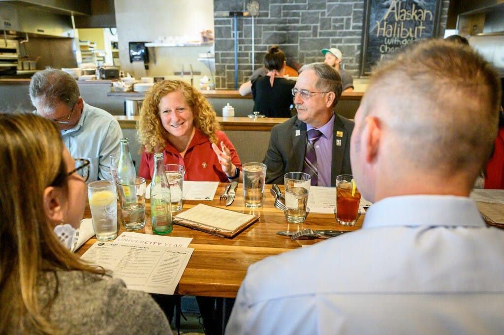 People gather around a table in a diner and talk.