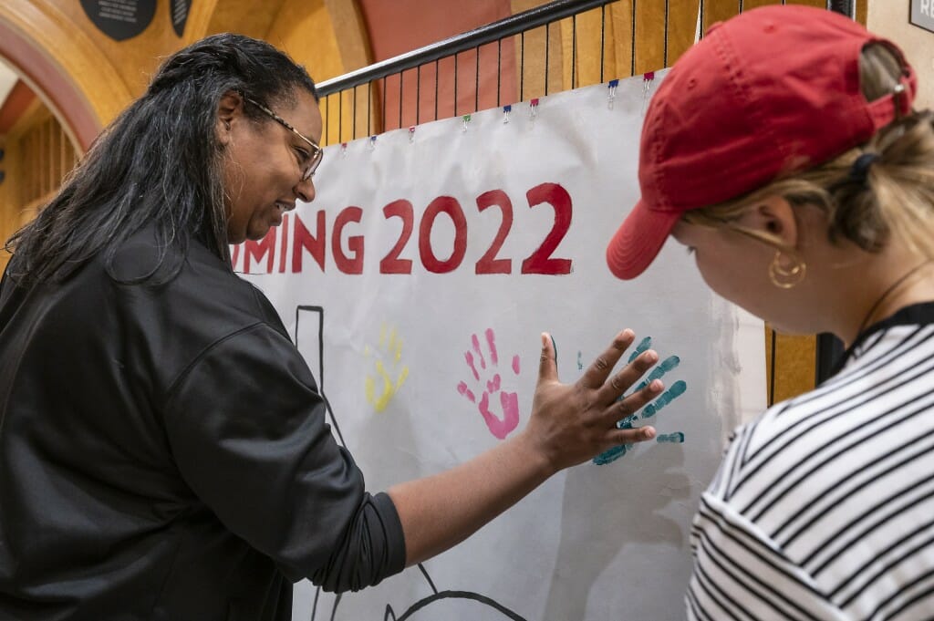 A woman makes a handprint on a canvas.